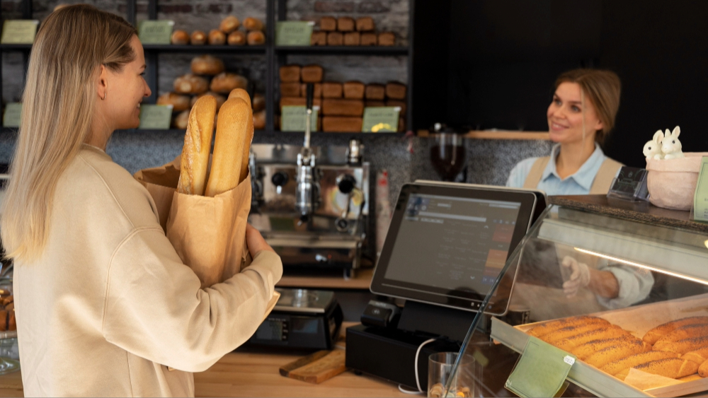 cliente y cajero de panadería con pantalla de sistema POS